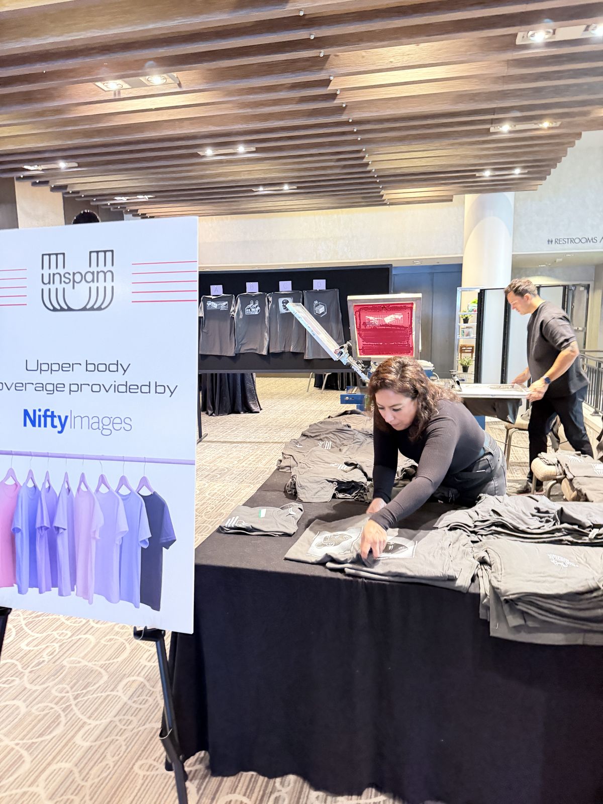 Crew members staging folded shirts on long tables in a hotel foyer before an event